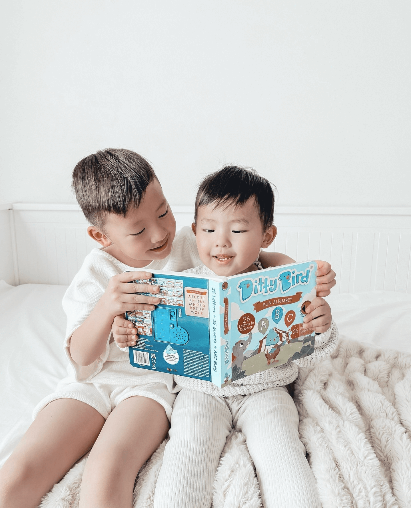 Two young children smile and read the Ditty-Bird AUS ABC Fun Alphabet, a USB-C rechargeable interactive book, building early literacy skills together as they enjoy each colorful page.